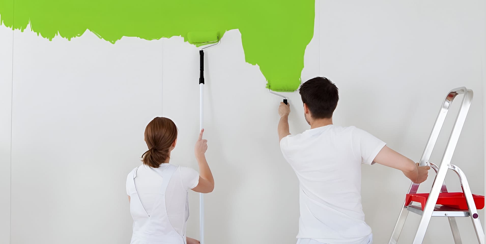 A man and woman painting the wall green.