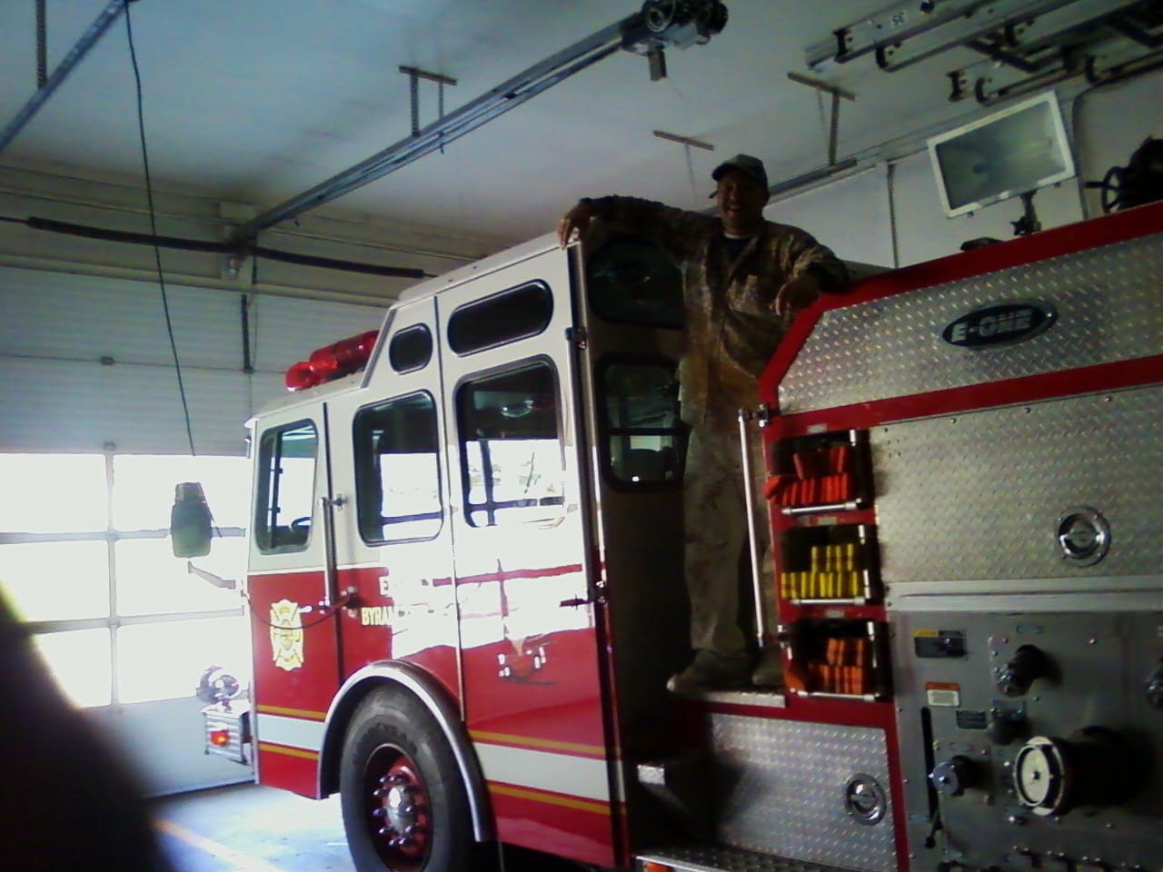 A man standing on the back of a fire truck.