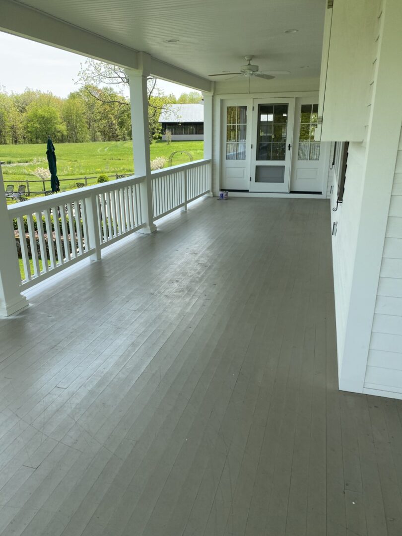 A porch with white walls and wooden floors.