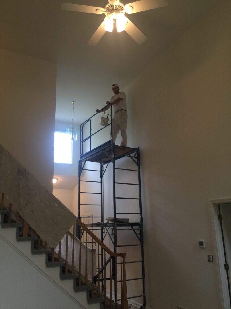 A man standing on top of a metal ladder.